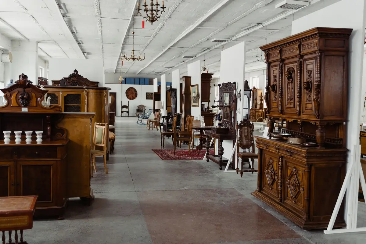 A long room of antique wooden cabinets, dressers and chairs set out for viewing, like the preview of an estate sale
