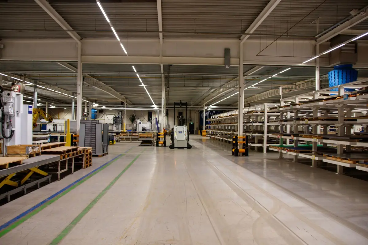 A large industrial warehouse floor with machinery, pallets and storage racking, the kind of mixed inventory a liquidation sale catalogs